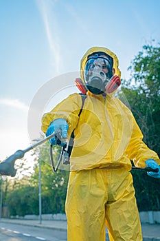 Coronavirus. A sanitation worker wearing a mask and cleaning the streets. Sterilize urban decontaminate city. Disinfecting against