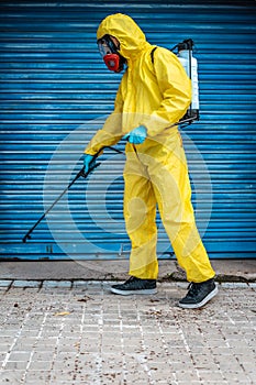 Coronavirus. A sanitation worker wearing a mask and cleaning the streets. Sterilize urban decontaminate city. Disinfecting against