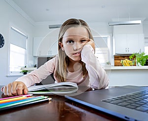 Coronavirus school closures and lockdown. Bored child with face mask studying online class at home