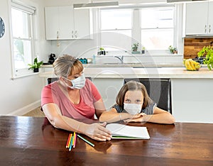 Coronavirus school closures and lockdown. Mum and bored daughter with masks studying online at home