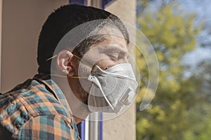 Coronavirus. Sick man of corona virus  looking through the window and wearing mask protection and recovery from the illness in hom