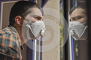 Coronavirus. Sick man of corona virus  looking through the window and wearing mask protection and recovery from the illness in hom