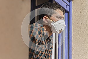 Coronavirus. Sick man of corona virus  looking through the window and wearing mask protection and recovery from the illness in hom