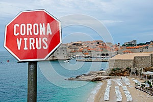 Coronavirus sign against view of walls and beach in Dubrovnik, Croatia. Warning about pandemic in Croatia. Coronavirus disease.