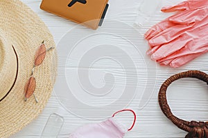 Coronavirus summer 2020. Pink face mask, gloves, antiseptic and disinfectant, passport, sunglasses,straw hat on white background.