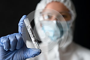 Doctor in medical PPE suit holds tube of COVID-19 PCR test photo