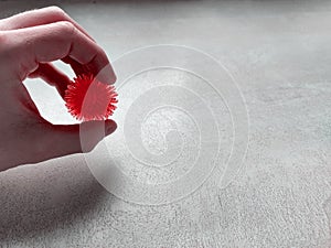 Coronavirus symbol in male palm on white textured table, rubber bowl with red spikes in the shape of a coronavirus virus photo