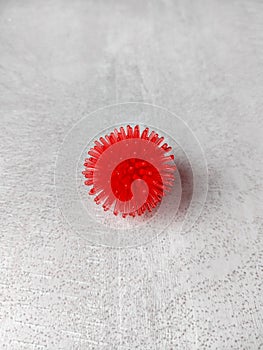 Coronavirus symbol on white textured table, rubber bowl with red spikes in the shape of a coronavirus virus photo