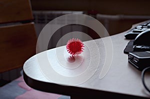 Coronavirus symbol on white textured table, rubber bowl with red spikes in the shape of a coronavirus virus, red ball for massage photo