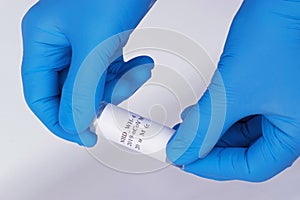 Coronavirus test sample or Covid-19 vial held between the blue gloved hands of a lab technician