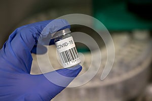 Coronavirus vaccination analysis in a microbiology laboratory. Scientist with gloves holding a vaccine during the covid-19 pandemi