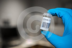 Coronavirus vaccination analysis in a microbiology laboratory. Scientist with gloves holding a vaccine during the covid-19 pandemi