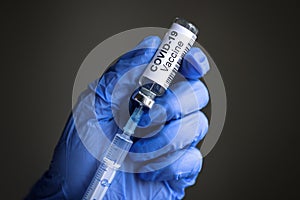 Coronavirus vaccine bottle and syringe for COVID-19 cure in doctorÃ¢â¬â¢s gloved hands photo