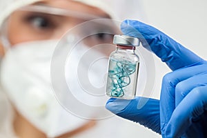 Coronavirus vaccine concept,UK doctor medical lab scientist holding glass phial ampoule containing COVID-19 vaccine