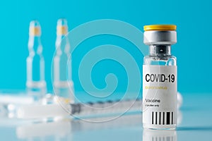 Coronavirus vaccine vial glass with a syringe on blue background.  Covid-19 medicine vaccination concept. World pandemic concept