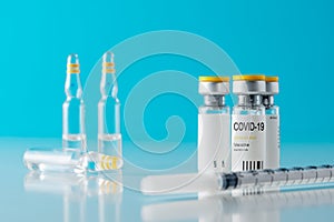 Coronavirus vaccine vial glass with a syringe on blue background.  Covid-19 medicine vaccination concept. World pandemic concept