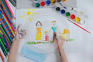 Coronavirus.Virus Covid 19-NCP.A child draws his family in masks on white paper with gouache paints.Next to the mask and photo