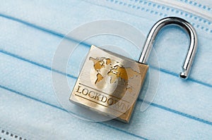 Coronavirus world lockdown end: a lock with a world map and the word lockdown engraved on a light blue surgical mask photo