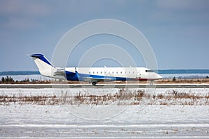 Corporate aircraft taxiing on the runway in a cold winter airport