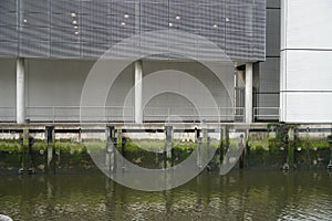 Corporate building above a concrete wall of riverbank in one channel of river Nieuwe Maas in Rotterdam