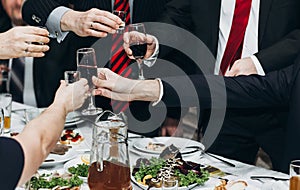 Corporate business man toasting at dinner party table hands close-up, wedding reception guests toast alcohol drinks in glasses