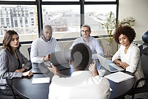 Corporate business people in a meeting room listening to a colleague speaking, elevated view photo