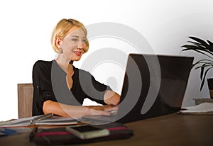 Corporate business portrait of young beautiful and happy woman with blonde hair smiling while working relaxed at office laptop com