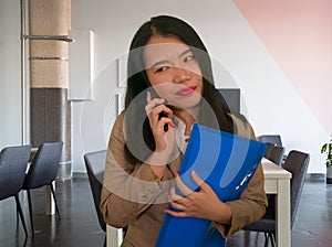 Corporate business stress portrait of young attractive and stressed executive Asian Chinese woman tired and unhappy talking on