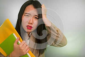 Corporate business stress portrait of young attractive upset and stressed executive Asian Chinese woman tired and unhappy holding