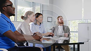 Corporate business team sitting in meeting room listening to leader