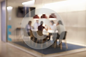 Corporate business team at table in a meeting room cubicle, defocussed