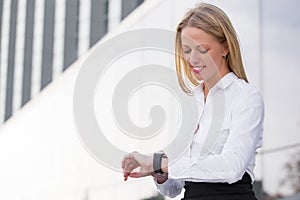 Corporate business woman looking at watch and smiling