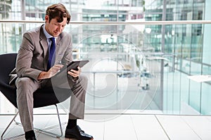 Corporate businessman using tablet computer, full length