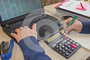 Corporate businessman working at office desk, he is using a calculator. Man doing his accounting, financial adviser working