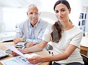 Corporate combo. two colleagues reading paperwork while sitting at a desk in an office.