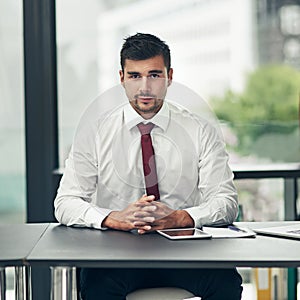 Corporate confidence. Cropped portrait of a young businessman sitting in his office.