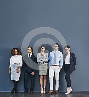 Corporate confidence at its best. Studio shot of a group of businesspeople standing in line against a gray background.