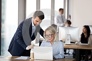 Corporate executive manager consulting mature employee helping with computer