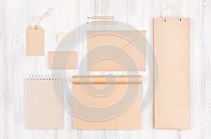 Corporate identity template; packaging, stationery, gift mock up of brown kraft paper on soft white wood background.