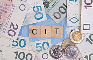 Corporate income tax in Poland, text CIT and Polish banknotes and coins on blue background photo