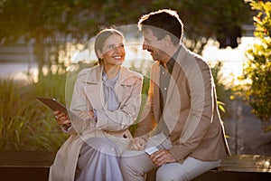 Corporate mature man and woman sitting at park, talking business