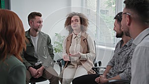 corporate meeting, a young confident woman talks to her colleagues during psychological training while sitting in a