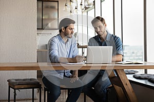 Corporate mentor explaining content on laptop to intern