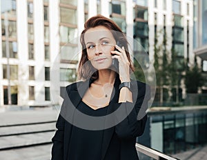 Corporate person with ginger hair standing outdoors and having a conversation by smartphone