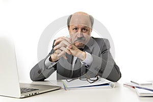 corporate portrait of 60s bald happy business man smiling confident and satisfied sitting at computer laptop office desk