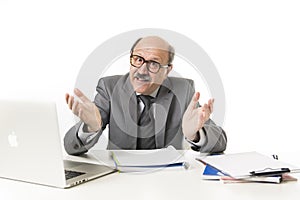 corporate portrait of 60s bald happy business man smiling confident and satisfied sitting at computer laptop office desk working