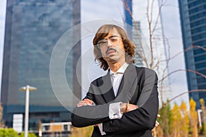 Corporate portrait of alternative businessman in a business park with arms crossed