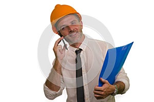 Corporate portrait of attractive and successful industrial engineer or contractor man in working hardhat talking on mobile phone