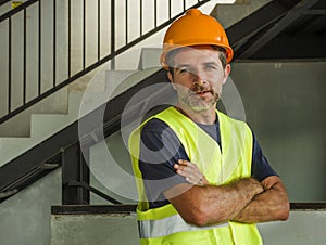 Corporate portrait of young attractive and happy builder man or constructor posing confident smiling wearing building helmet and