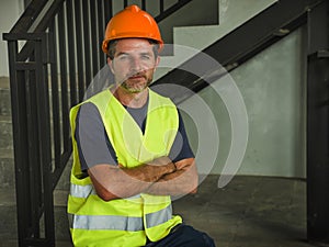 Corporate portrait of young attractive and happy builder man or constructor posing confident smiling wearing building helmet and